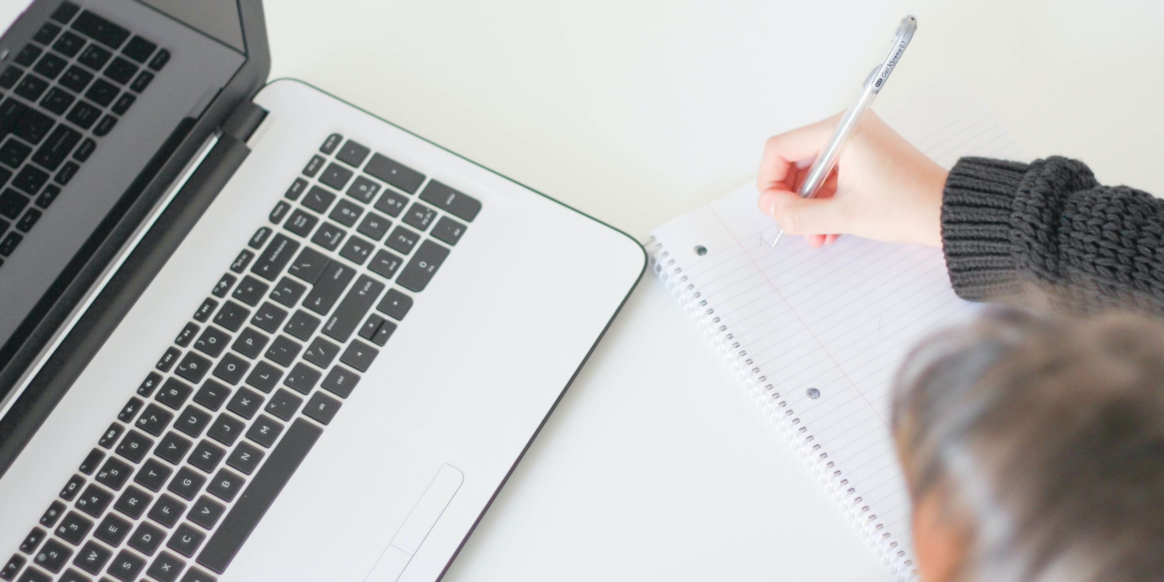 a person taking notes near a laptop