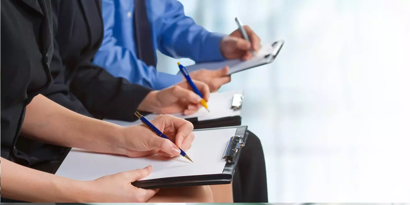 closeup of three hands writing on paper