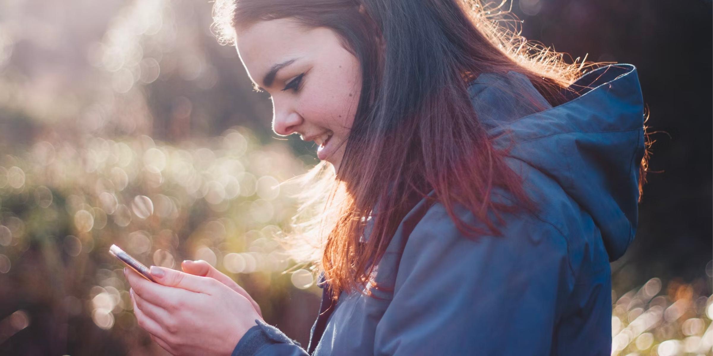 closeup of a student smiling at their cell phone