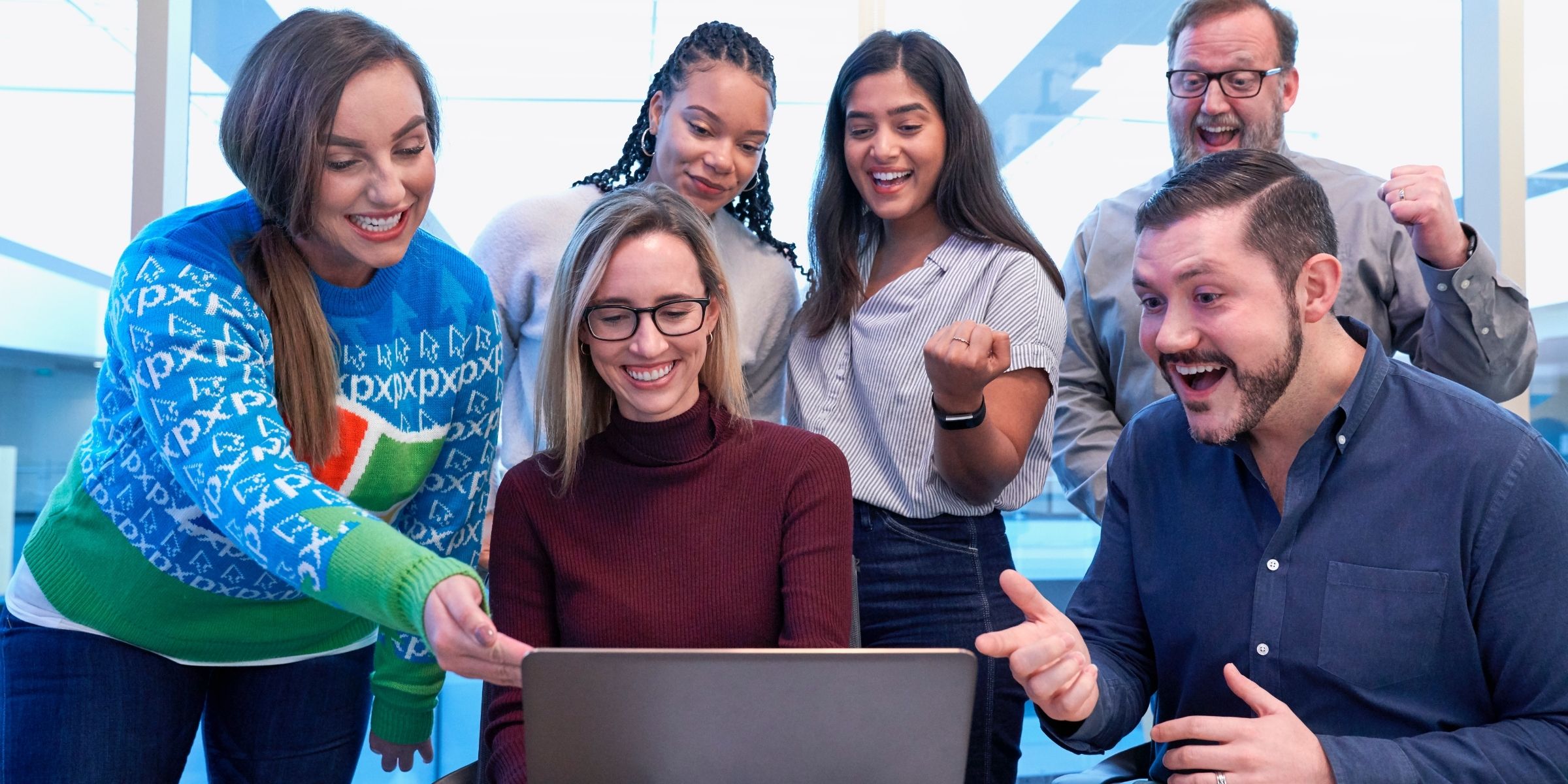 people smiling and celebrating while looking at a computer