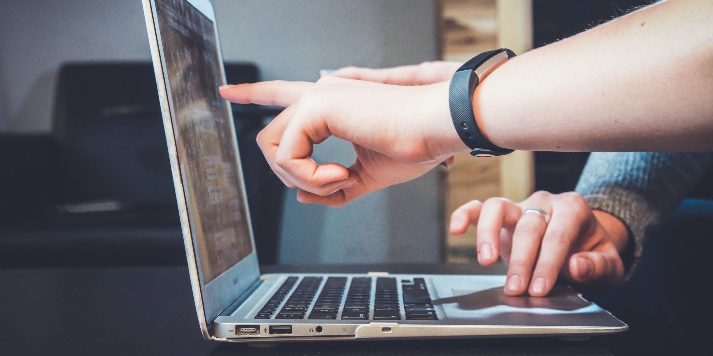 a student's hand pointing at a laptop screen