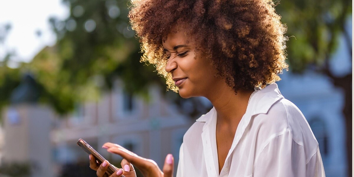 a person holding their cell phone in one hand while holding their other hand out in the air, clearly annoyed at what they're seeing on their phone