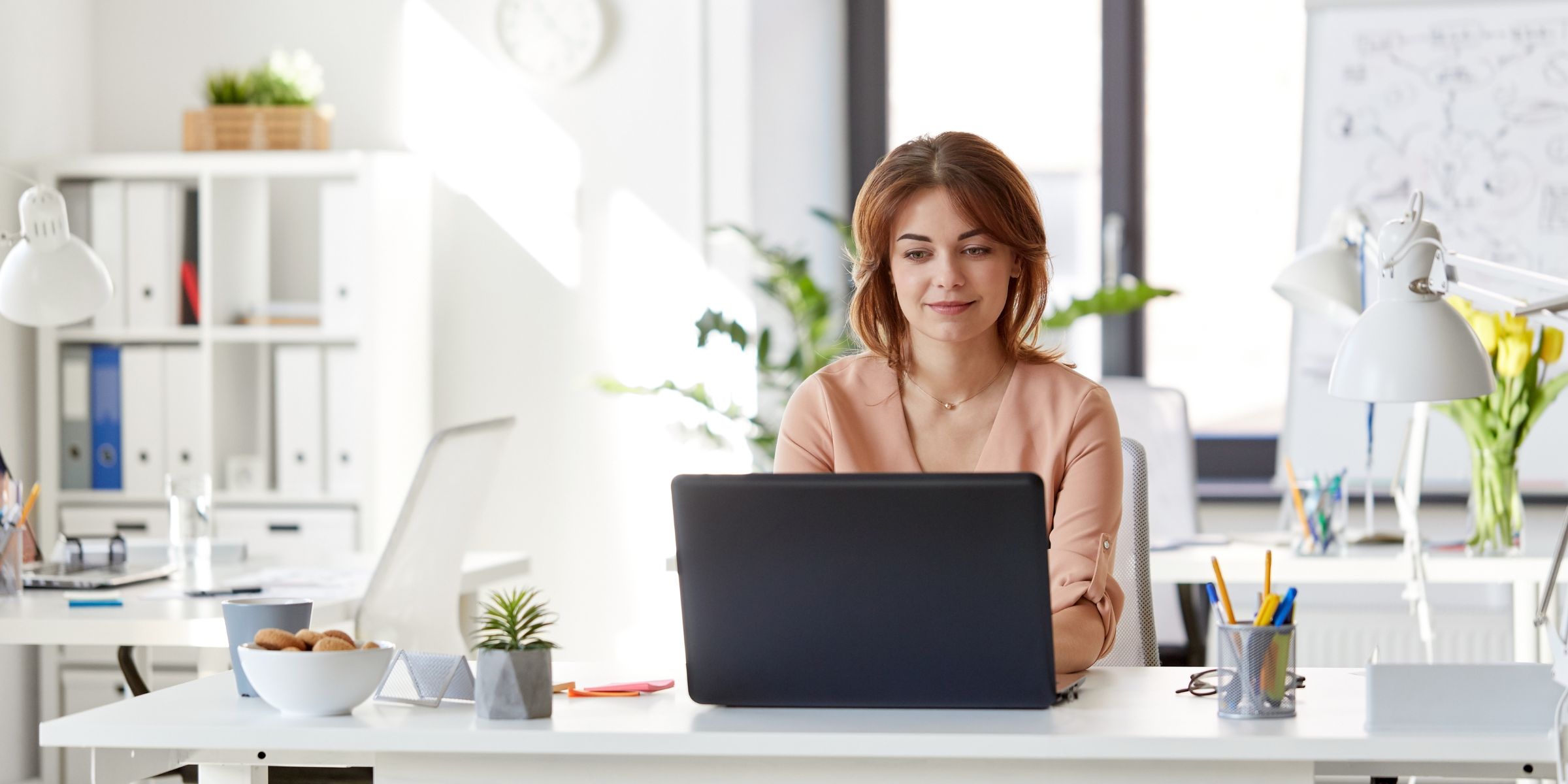 a woman typing on a laptop and smiling